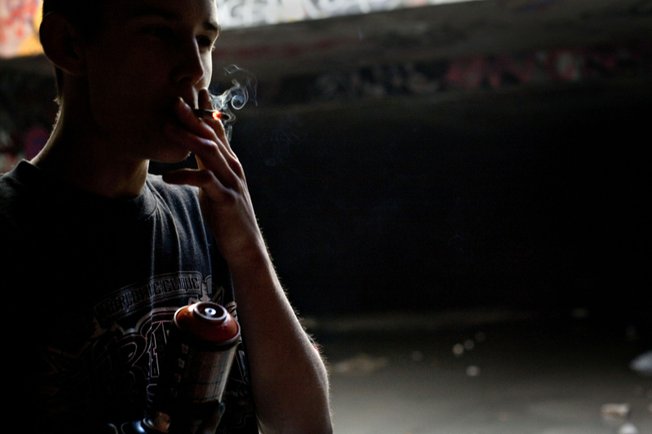 Ruckoh takes a drag on a cigarette while working on a mural.