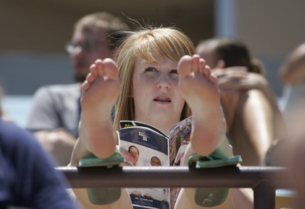Haley Grenz protects her feet from a hot railing-- with her flip flops-- while watching a Las Vegas 51's day game. 