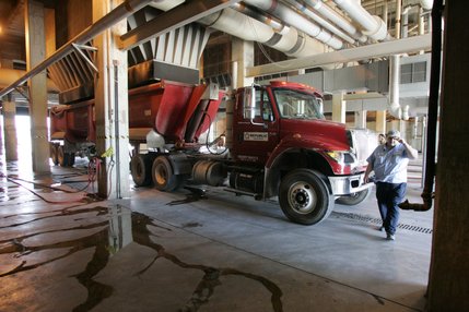 Solid waste drops out of the compressors above into trucks for transport to a landfill.  