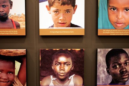 Millions of people are forced to flee their homes due to war and violence.  Photographs of refugee children from various countries greet viewers as they enter the refugee camp in 