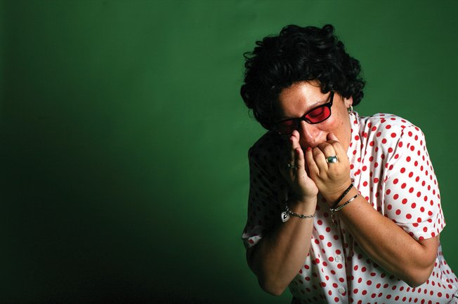 Corvello demonstrates her versatility in playing air instruments, showing off her technique on the air harmonica.