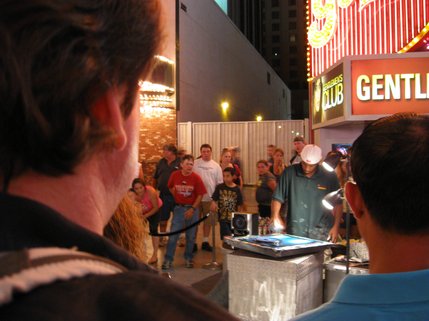A crowd gathers to watch an artist hone his craft. 
