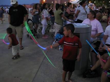 A boy plays with a glow stick as he and his family wait for the fireworks to begin. 