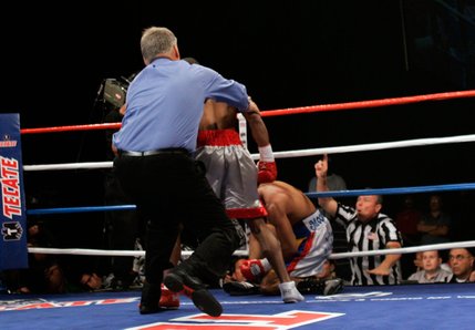 Referee Jay Nady pulls Kendall Holt away from WBO junior welterweight champion Ricardo Torres after Holt knocked down Torres in the first round.
