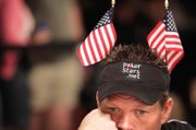 Noble Simpson of Jena, La., wears a pair of American flags as he mulls a hand. More than 1,000 flags from countries around the world were passed out at the beginning of the day.