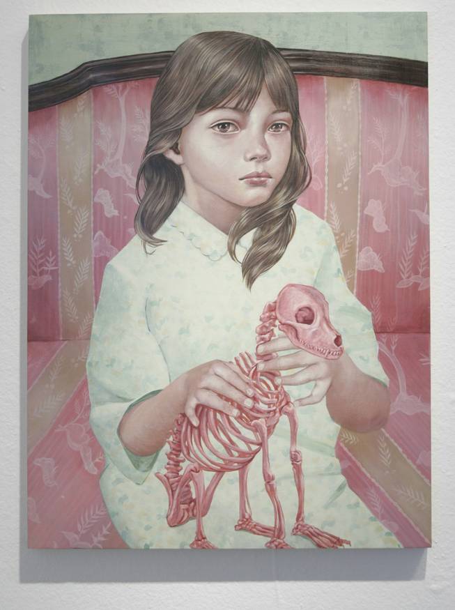 
Something is off kilter: The young girl in a flannel nightie sitting on a Victorian settee holding the pink skeleton of a pet dog creates a perfectly ambiguous scene.