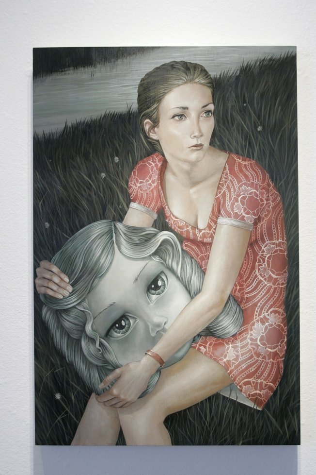 There is a sad dose of reality: The young woman, caught between childhood and adulthood, sits in the grass by the river in a patterned, low-cut minidress, holding the head of a "dollified child."
