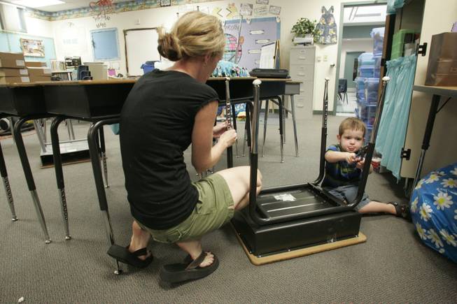 Wendy Adams, a teacher at Tony Alamo Elementary School, readies her fourth grade classroom for the upcoming school year with her son Jaden on Thursday. With cuts to school funding, teachers are spending much of the money they receive from the district on basic supplies. 