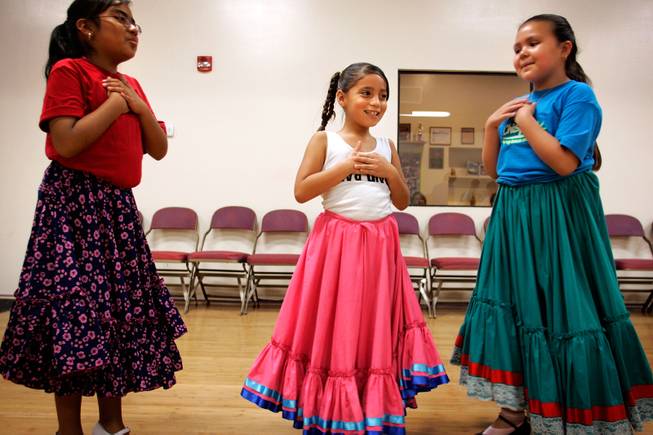 After a breathless round of rehearsing ballet folklorico, traditional Mexican folk dance, at the Viva Performing Arts Center in Tucson, 8-year-old friends, from left, Kiana Medrana, Sofia Espinoza and Gabriella Carrillo feel their chests for their quickened heart beats, giggling at how fast their hearts are beating after a good round of dancing. -- Leila Navidi