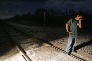 An alleged illegal immigrant stands by a railroad track after being spotted by the Minuteman Civil Defense Corps of Arizona on a private ranch near Amado, Ariz. The rancher asked the Minuteman Corps to set up a muster, or a border watch operation, to look for illegal immigrants using his ranch to avoid a Border Patrol checkpoint on Interstate 19, a road that comes south toward Tucson, Ariz., from Nogales, Sonora, Mexico. The rancher suspected that the immigrants were dropped off south of the border checkpoint, making their way on foot through his ranch, to be picked up by car on I-19 at a designated area north of the checkpoint. This man was the last of 13 people spotted by the Minuteman Corps, and then picked up by the Border Patrol that night. 