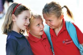 Happy to be together again, best friends and first-grade classmates, from left, Courtney Martin, Dani Dennis and Kennedy Steele, cuddle together before the whistle blows on the first day at Henderson International School's Windmill Campus.