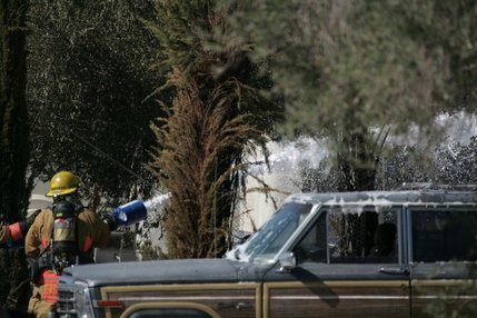 Firefighters spray fire retardant on a house after a twin-engine Piper Navajo crashed into a home on North Jones Boulevard near Cheyenne Avenue today.