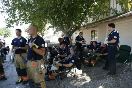 Firefighters cool off under a tree in front of a house on North Jones Boulevard after battling a blaze Thursday afternoon that erupted after a twin-engine Piper Navajo crashed into a home on North Jones Boulevard near Cheyenne Avenue.