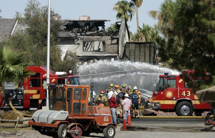 Firefighters work on putting out hot spots after a twin-engine Piper Navajo crashed into a home on North Jones Boulevard near Cheyenne Avenue Thursday, Aug. 28, 2008.  