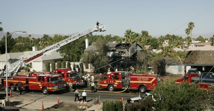Firefighters investigate a house fire on North Jones Boulevard near Cheyenne Avenue after a twin-engine Piper Navajo crashed into the home Thursday, Aug. 28, 2008.  