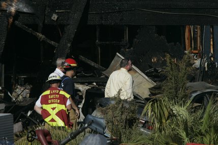 Officials look over a home after a twin-engine Piper Navajo crashed into the home on North Jones Boulevard near Cheyenne Avenue Thursday, Aug. 28, 2008.  