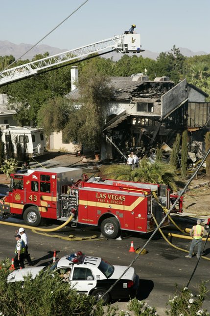 Firefighters look over a home after a twin-engine Piper Navajo crashed into the home on North Jones Boulevard near Cheyenne Avenue Thursday, Aug. 28, 2008.  