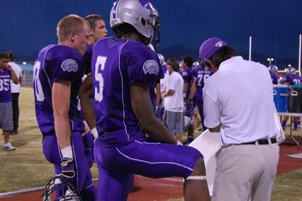 Senior Alex Jones listens to a play with other teammates on the sideline.