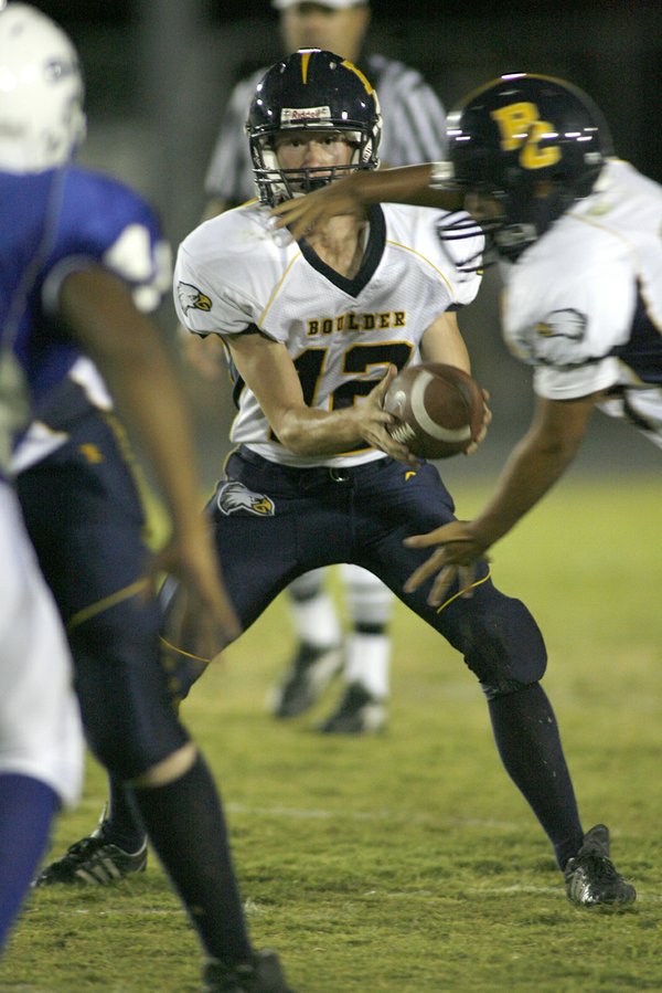 Boulder City high quarterback Jake Phillips (12) hands off a ...