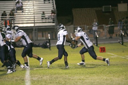 Centennial quarterback Chris Henderson hands off a pass to Josh Hardy (30) during an away game against Green Valley on Friday night. 