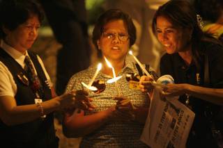 From left, Carmen Santos, Shirley Lahaylahay and Victoria Takatlashi light their candles during a candlelight vigil organized by the SEIU at St. Rose Hospital on Sept. 10. The women are nutrition service workers.