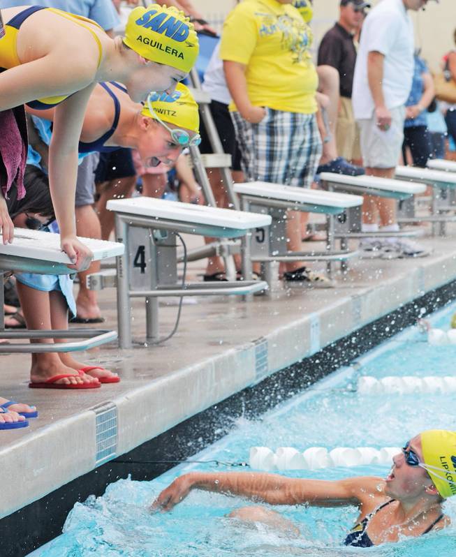 Alexa Aguilera, 12, top left, and Maddie Lipkowitz, 12, shout encouragement to Natalie Lipkowitz, 16, as she kicks off the wall while competing in the 100-meter butterfly during the 22nd annual Desert Invitational at the Henderson Multigenerational Center.