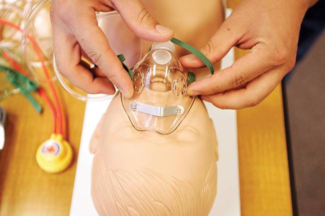 A student practices placing an oxygen delivery mask on the face of a doll in a neonatal and pediatrics lab at the College of Southern Nevada.