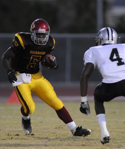 Dragon running back Earnest Hall (5) looks to sidestep Palo Verde tackler Sidney Hodge (4) during a game at Del Sol High School on Friday.