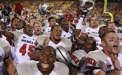 UNLV players including Wiselet Rouzard, front left, Casey Flair, front right, and Marquel Martin (45) celebrate with teammates after their upset overtime win over Arizona State.