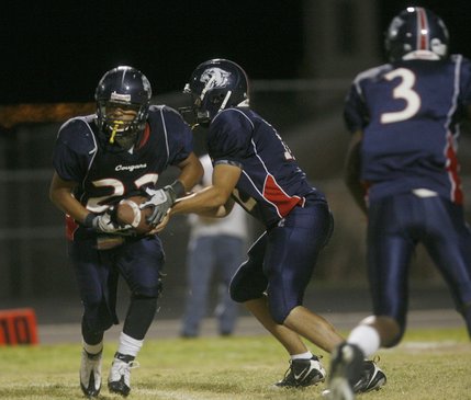 Coronado quarterback Michael Scott (12) hands a pass to Marcus Garcia (22) during Friday's home against Basic.
