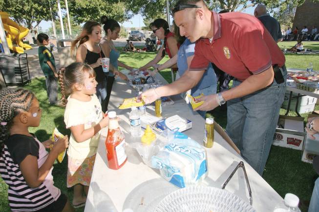 Police officer Gus Leigh hands out potato chips during a block party at Wells Park in Pittman.