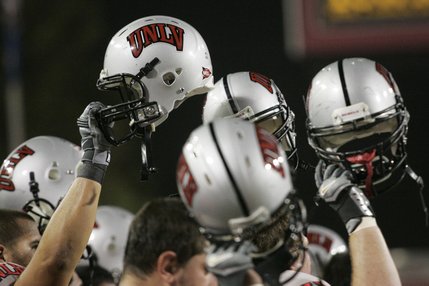 UNLV players raise their helmets at the start of the game against UNR at Sam Boyd Stadium.