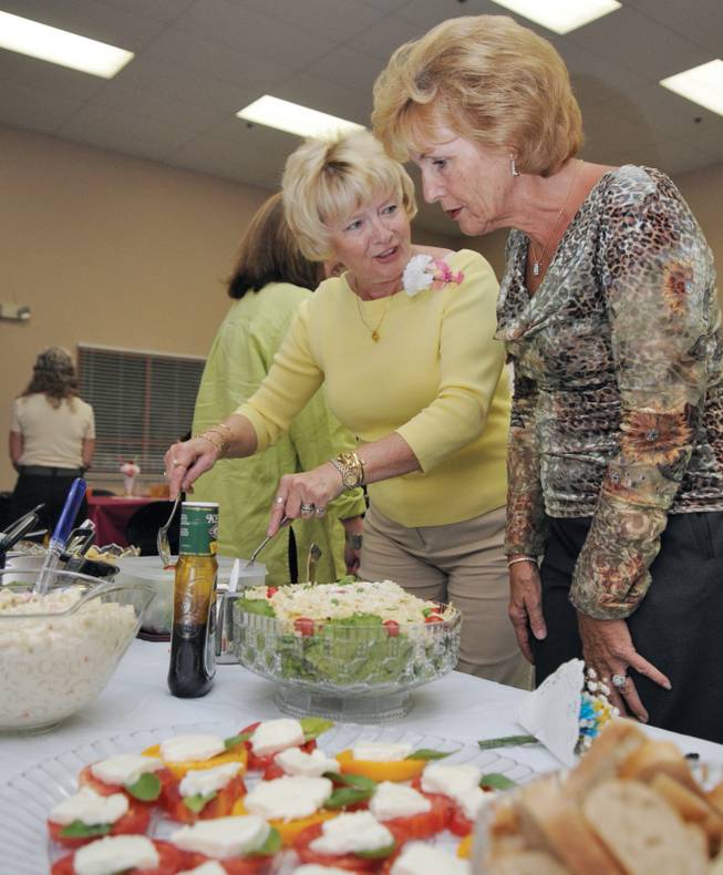 Sheila Eberle, left, converses with Karin Mavis as she puts the finishing touches on a salad in preparation for the start of a potluck dinner meeting of the Women's Club of Summerlin.