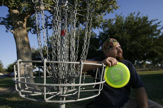 Disc golfer Robert Schuler, a member of the Professional Disc Golf Association, poses next to a disc golf basket Wednesday at Sunset Park. He's worried that upcoming renovations at the park will affect the course.