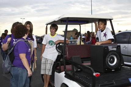 Sophomore J.T. McClain and freshman Justin Telford, right, show off their golf cart equipped with a stereo and subwoofer to the judges during the high school car contest during at Friday's homecoming tailgate party at Silverado High School.