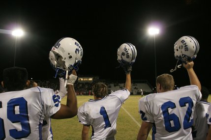 From left, Basic players Richard Castillo (59), Joe Baker (1) and Erick Rubeck (62) hold up their helmets during Friday's away game against Liberty.