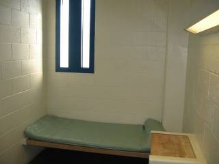 The bed and desk in the jail cell. 