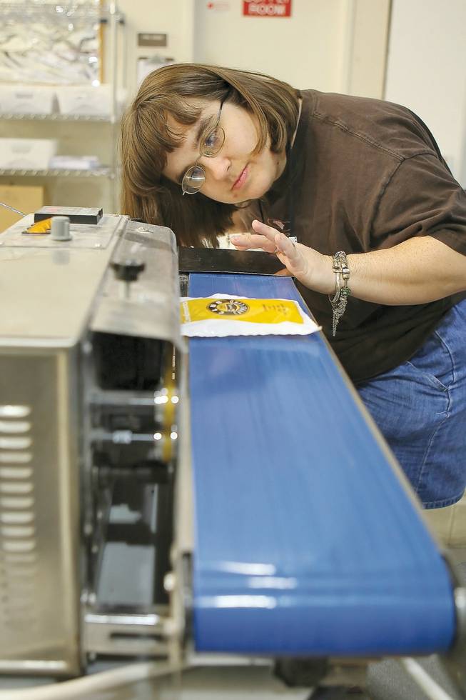 Manning the conveyer belt, production associate Kelly Cooksey seals one of 200,000 condiment packs prepared monthly for Harrah's Corporation in the Employment Training Center at Opportunity Village.
