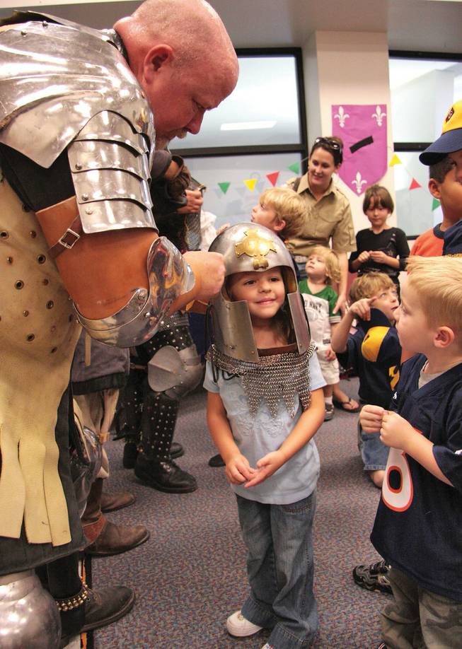 Earl Sir Matthias places his helmet on 5-year-old Bryn Christopher at the "The Age of Chivalry" medieval exhibition for kids ages 6 to 11 at the Sahara West Library to promote the upcoming Las Vegas Renaissance Festival at Sunset Park. 
