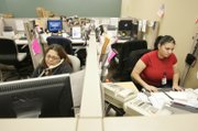 Tricia Benavente, left, helps a voter on the phone while Martha Barraza inputs a voter registration card Thursday.