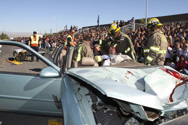 After cutting the roof off a vehicle during the Every 15 Minutes program at Coronado High School, Henderson firefighter/paramedics of Truck, Engine and Rescue 98 rush to the aid of seniors Paige Johannessen and Jared Kuhlmann, right, while participating in a simulated alcohol-related car crash Oct. 16.