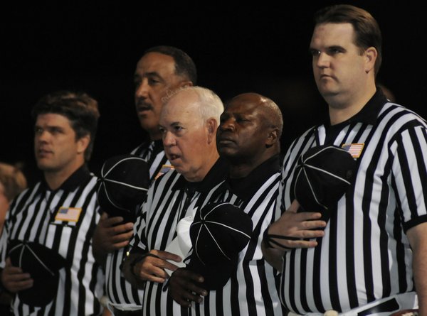Football officials remove their caps during the national anthem Friday ...
