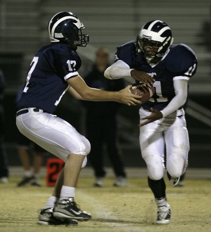 Shadow Ridge quarterback Matt Rodman hands the ball off to Alan Lundstrom.