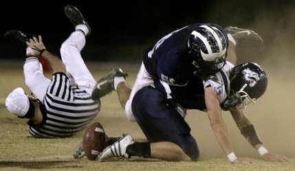 The referee gets knocked down as members of both teams try to recover the loose ball.