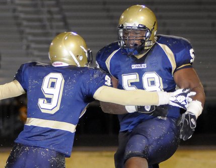 Spring Valley's Nate Holloway (58) celebrates a fourth-quarter sack of Bengals quarterback Sterling Sprau with teammate Aareon Smith-Allen (9) during the final minutes of Friday's game at Spring Valley High.