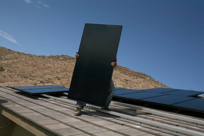 Electrician Frank Cudia of Bombard Electric carries a solar panel for installation this month on the roof of a home in Las Vegas. Developers of large solar arrays say Nevada doesn't offer kinds of the incentives or workforce other states do.

