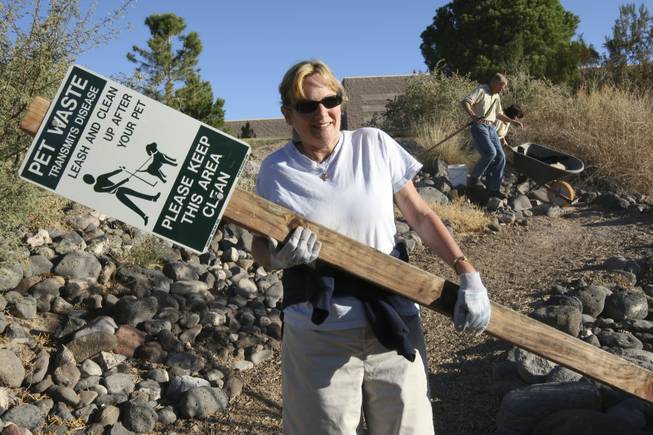 Pastor Marta Poling-Goldenne of New Song Church carries a sign Saturday to be placed along the trails of the Pittman Wash behind Silver Springs Recreation Center for Project Green Volunteer Make A Difference Day.