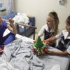 The Meadows kindergartners Mia Spilotro, center, and Ariana Sanatinia, right, give Dylan Aseph, left, a clown pumpkin during their visit to the UMC pediatric intensive care unit on Wednesday.