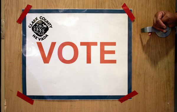 A poll worker leans on the door to Conference Room ...
