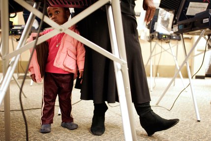 Roshida Muhammed, 2, stands patiently by her foster mother's side while she votes on Election Day at the West Las Vegas Library.